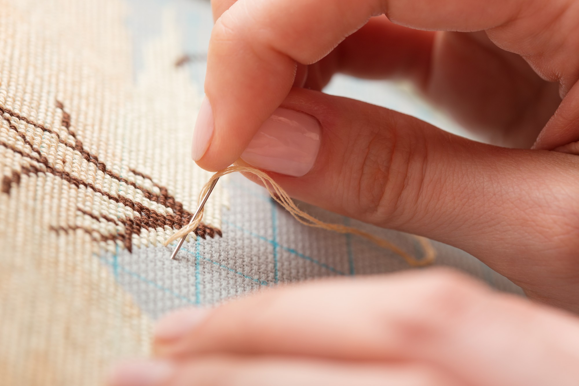 Hands stitching geometric pattern on linen